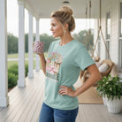 LULU MAC- OCD TEE IN DUSTY MINERAL WASH BLUE on model holding coffee mug in outdoor setting.
