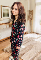 Woman wearing PEACE LOVE HOPE PJS with Christmas designs and red trim by Love To Sleep in a cozy bedroom setting.