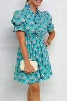 Woman wearing the Ruffled Romance Dress, featuring aqua floral print and frilled neckline, perfect for spring fashion.