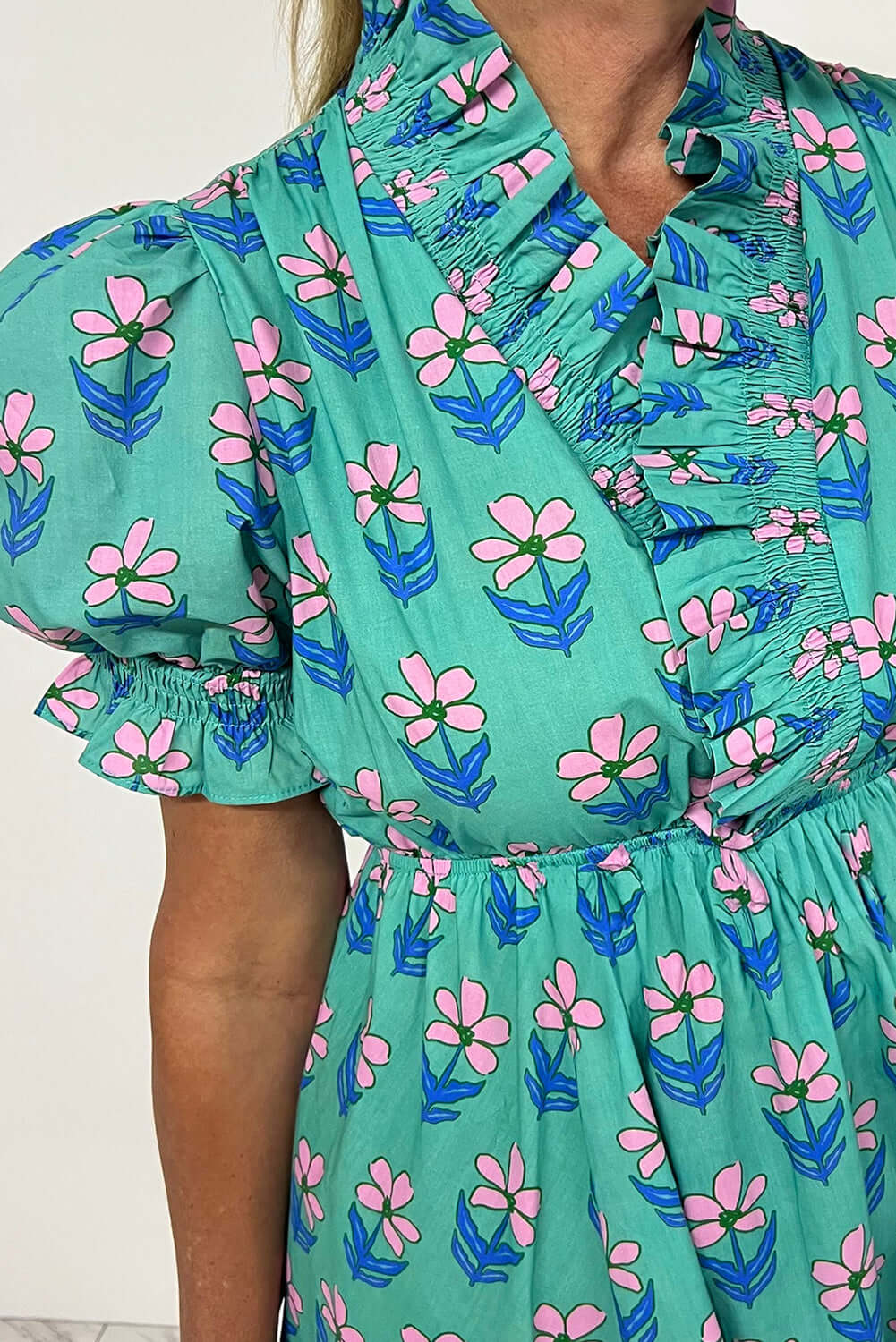 Ruffled Romance Dress featuring aqua floral print and frilled neckline, perfect for a feminine and playful look.