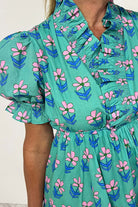 Ruffled Romance Dress featuring aqua floral print and frilled neckline, perfect for a feminine and playful look.