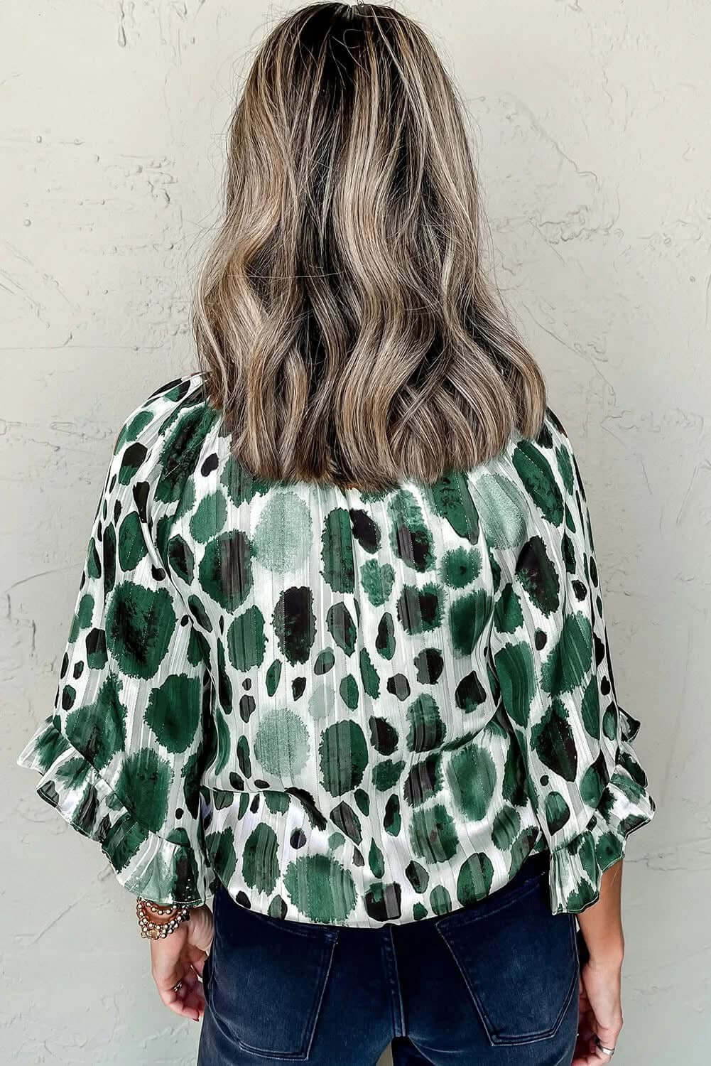 Back view of a women's Enchanted Valley blouse with green spotted design and ruffled sleeves.