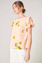 Blush yellow DAISY MARIE TOP by SugarLips featuring sunflower print and ruffle detail, perfect for spring styling.