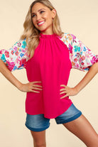 Woman wearing the pink Petal Passion Top with floral sleeves, styled with denim shorts for a trendy look.