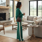 Woman wearing WINTER WEEKEND SET in sea green with varsity stripes, enjoying coffee in a cozy living room.