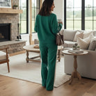 WINTER WEEKEND SET: Woman in sea green pullover and drawstring pants, enjoying coffee in cozy living room.