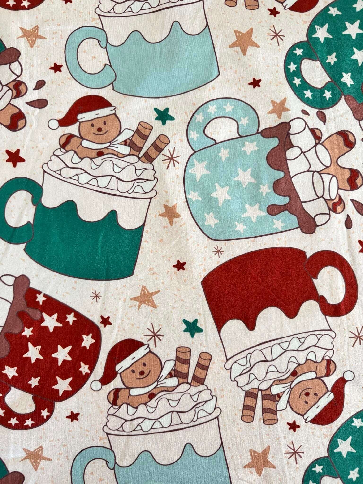 Festive holiday pajamas pattern with gingerbread men in cocoa mugs wearing Santa hats, surrounded by stars and candy canes.