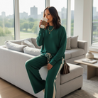 Woman in sea green WINTER WEEKEND SET, sipping coffee while lounging on a sofa with city view.