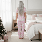 Back view of model in SUGARPLUM SANTA PAJAMA SET, showcasing festive design in cozy home setting.