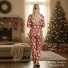 A woman in a KRIS KRINGLE KOZY Pajama Set stands by a cozy fireplace decorated for the holidays.