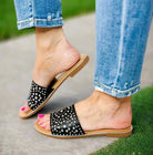 Corkys Bail Money sandals in black with studded wide strap, styled with torn blue jeans.