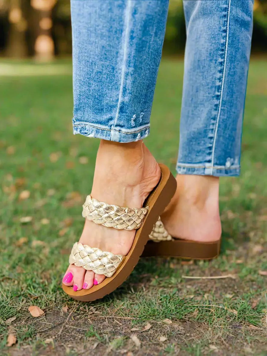 Corkys Wind It Up gold braided sandals on a woman’s foot, perfect for casual summer outings and stylish comfort.