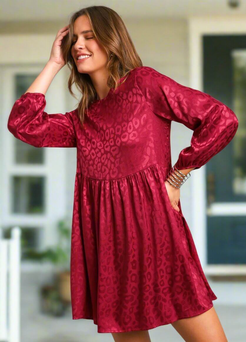 Woman wearing Scarlet Sensation Dress by Umgee, long sleeve, animal print, bronze jacquard, keyhole back, standing outdoors.