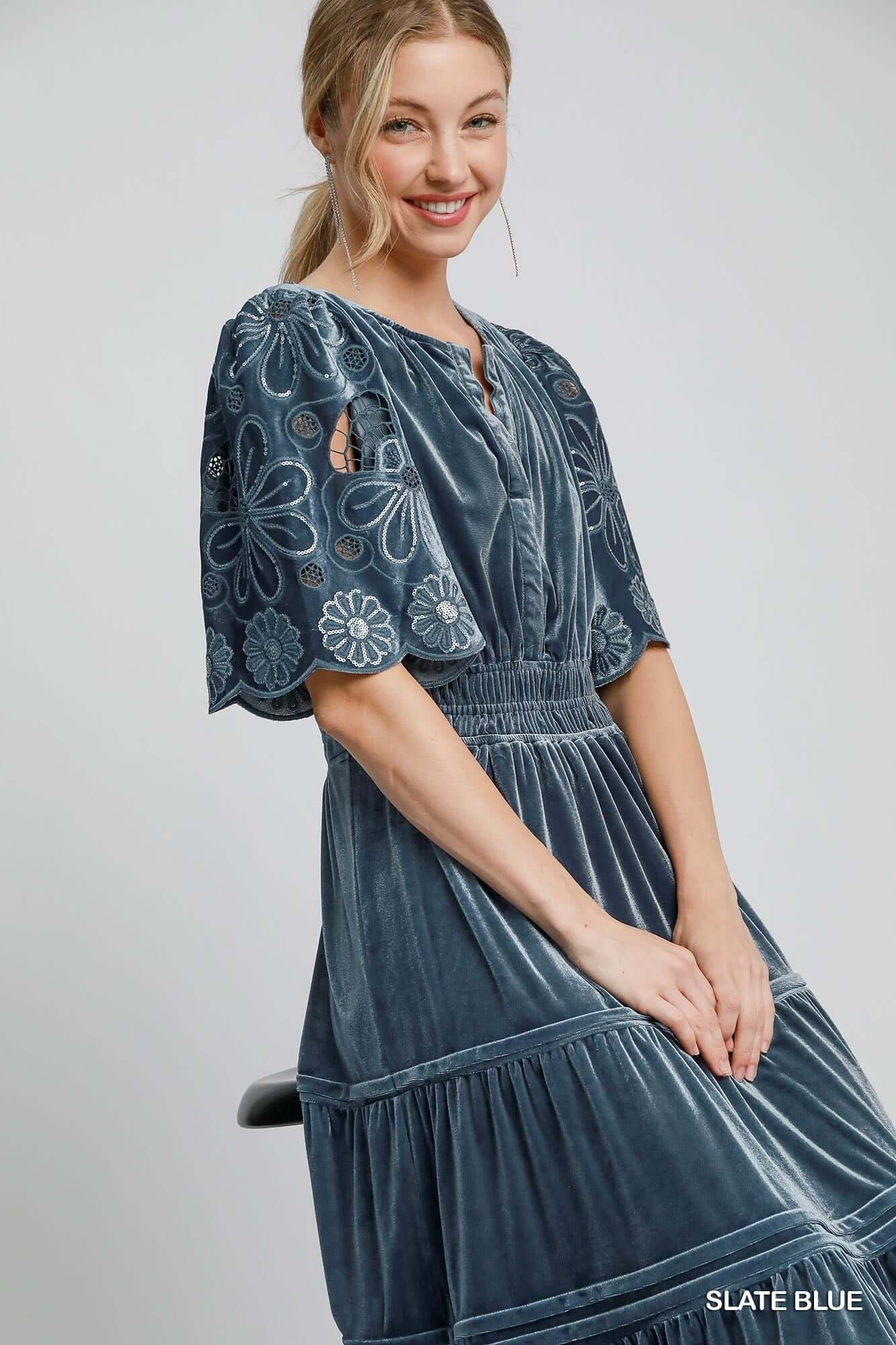 Woman wearing Umgee PURE HAPPINESS Dress in slate blue with floral lace contrast flutter sleeves and velvet fabric.