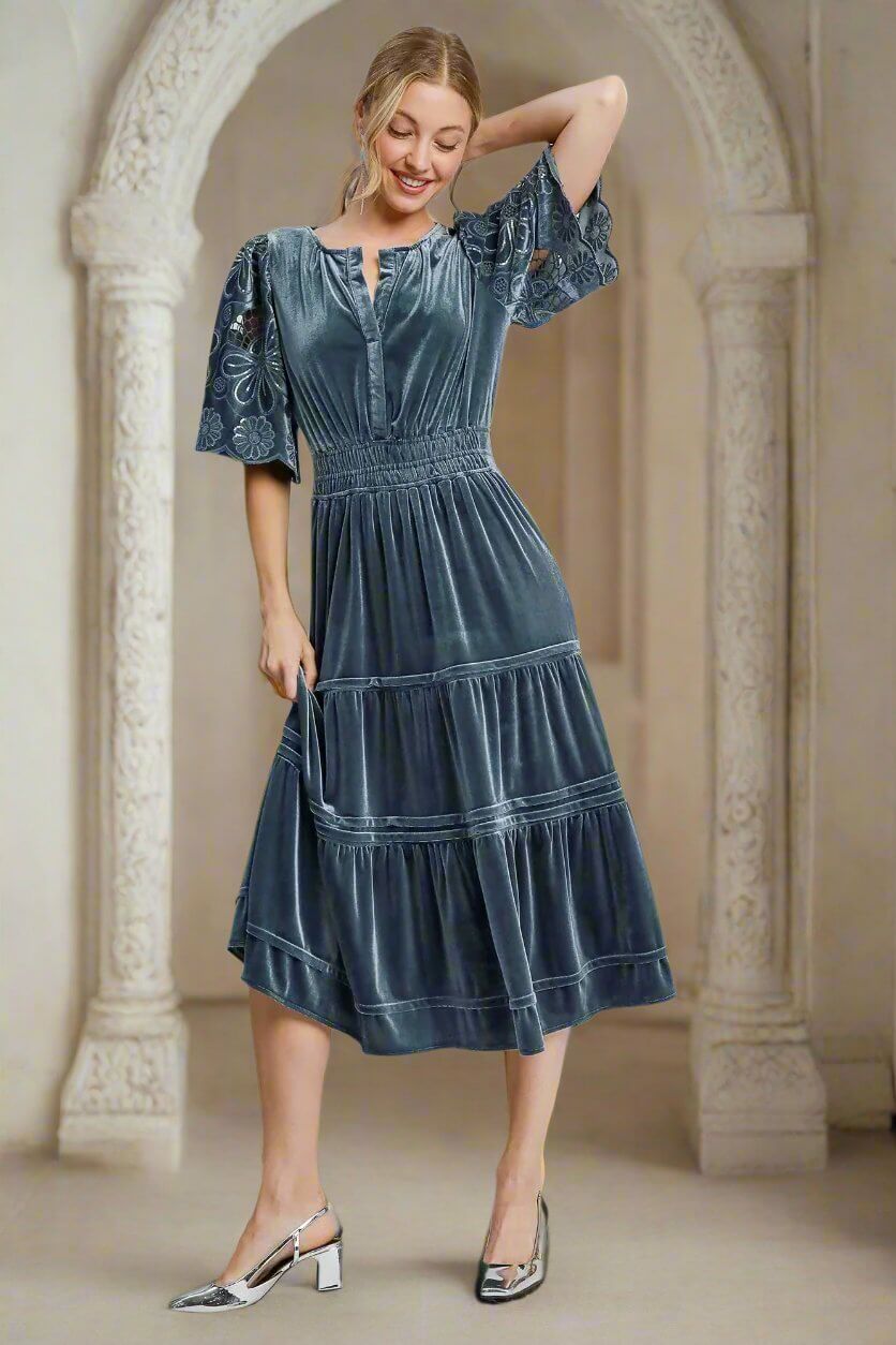 Woman wearing PURE HAPPINESS Floral Lace Contrast Sleeve Dress in slate blue velvet by Umgee, standing elegantly.