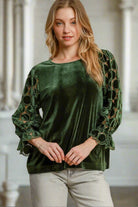 Woman wearing green velvet top by Umgee with lace polka dot 3/4 sleeves and ruffle cuffs, featuring a keyhole button closure.