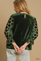 Woman wearing green velvet top with lace and velvet polka dot 3/4 sleeves, showcasing keyhole button back detail by Umgee.