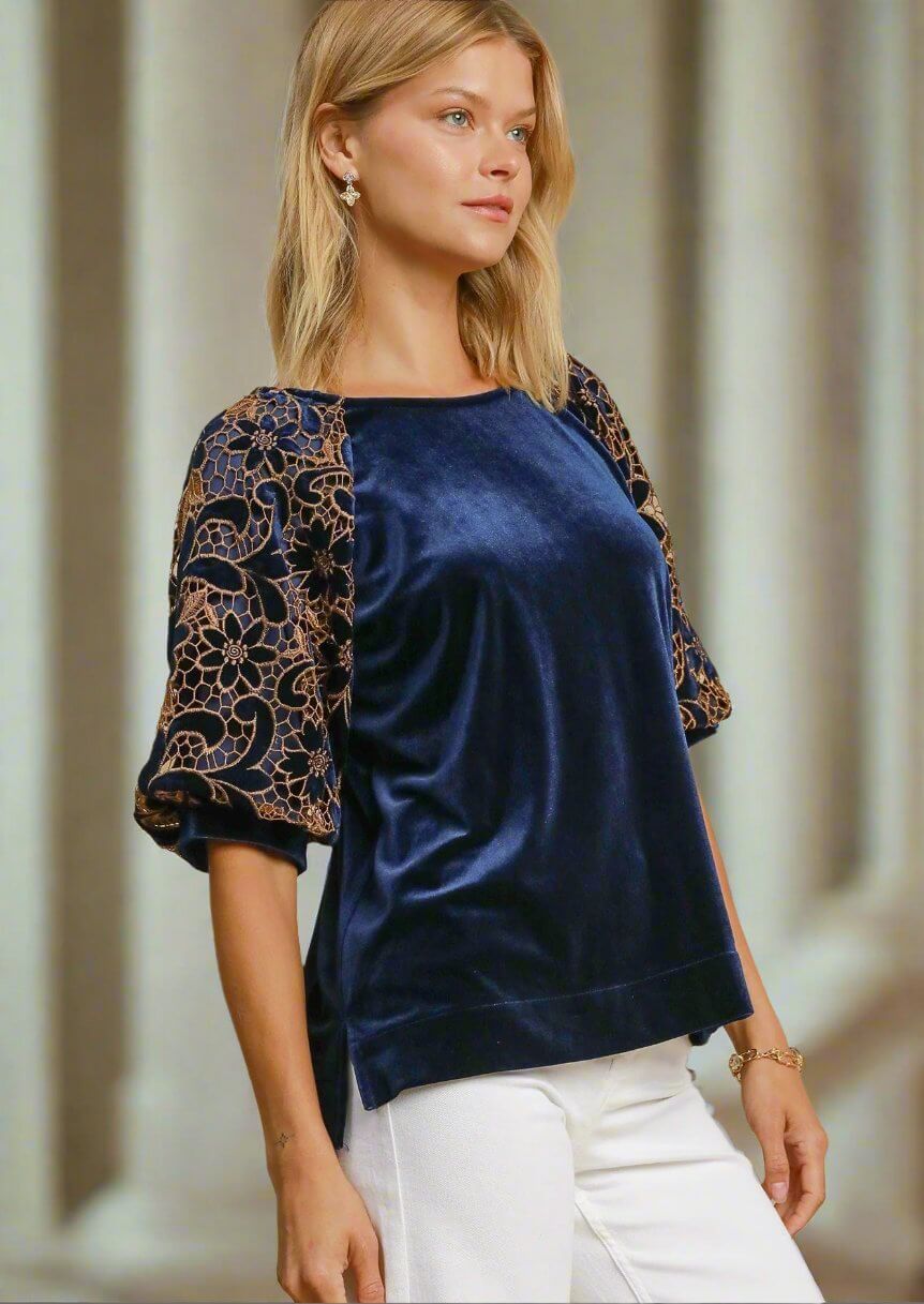 Woman wearing a navy blue velvet top with contrast floral lace poof sleeves, perfect for elegant events and evenings.