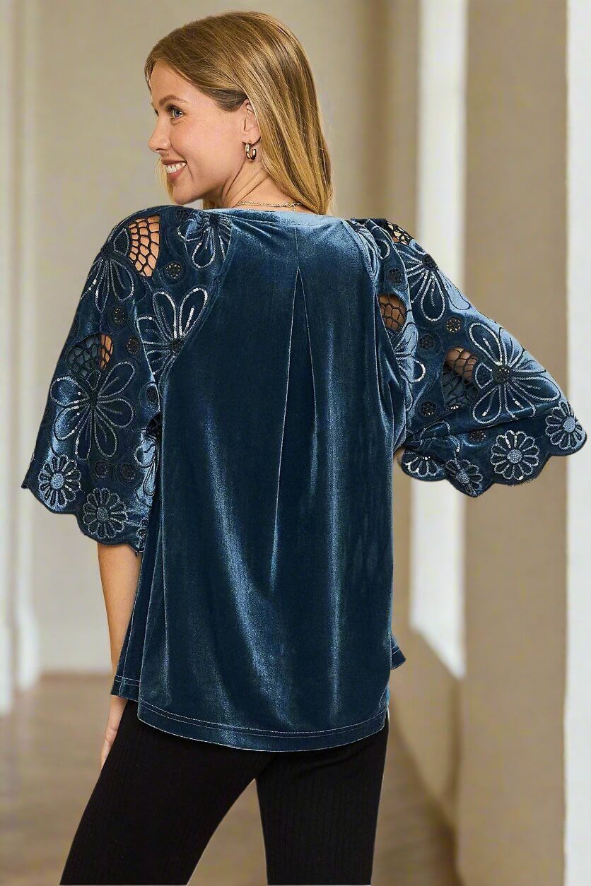 Woman wearing blue velvet top with embroidered flutter sleeves and pleated back, showcasing elegant style from Umgee's BRIGHT SPIRITS collection.