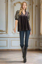 Woman wearing Umgee WAITING FOR MIDNIGHT top in dark espresso velvet with bubble sleeves and jacquard embroidery, paired with jeans and boots.