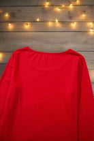 Red long sleeve top from SWEET DREAMS CANDY CANE Pajamas, perfect for cozy holiday lounging, with festive string lights in the background.