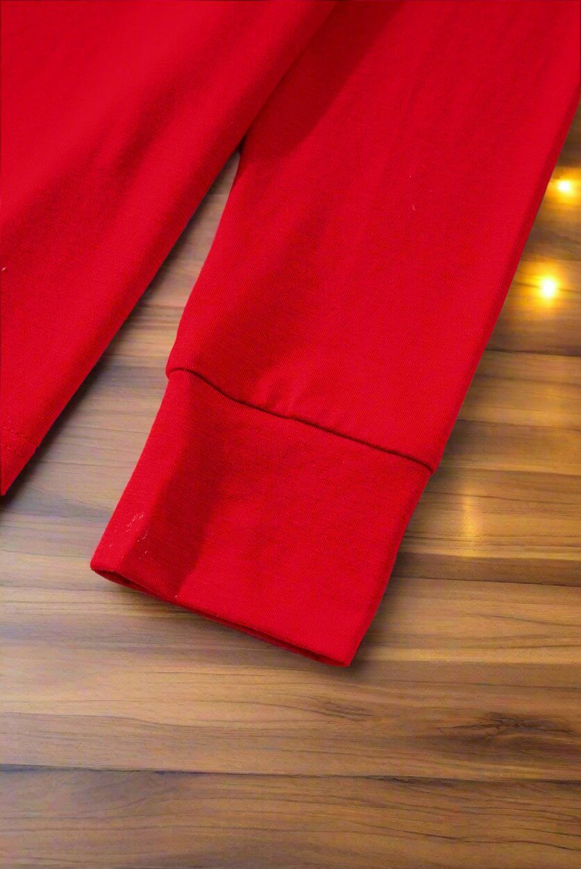 Close-up of red sleeve from Sweet Dreams Candy Cane Pajamas on a wooden surface.