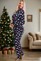 Woman wearing festive "BLUE CHRISTMAS WITHOUT YOU" pajamas, featuring colorful holiday designs, in a cozy living room with a Christmas tree.