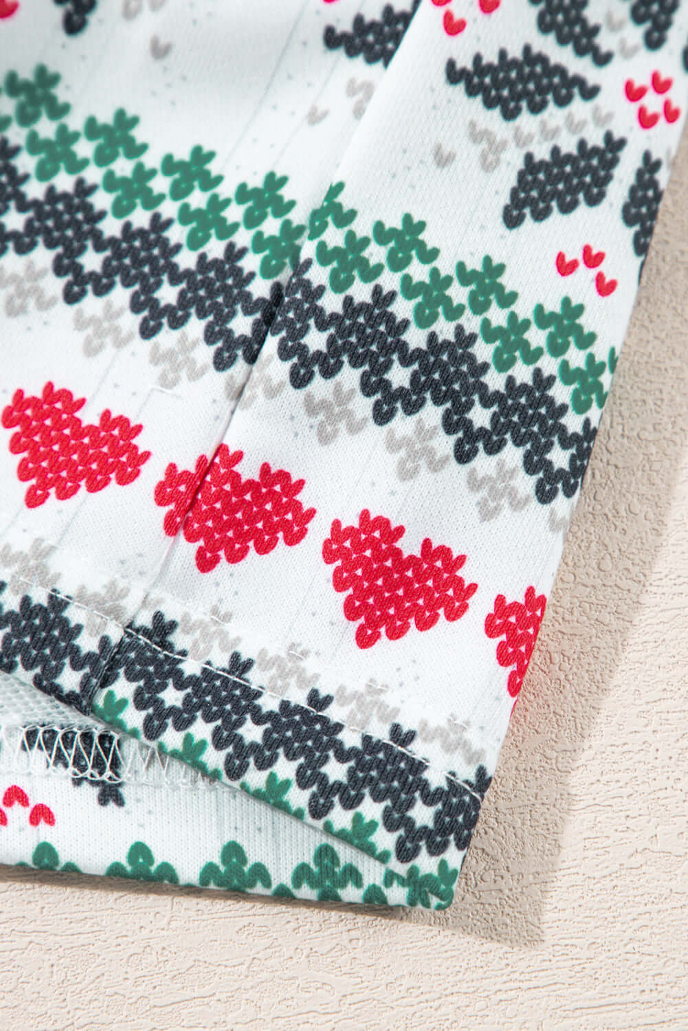 Close-up of festive pajama fabric with red, green, and black snowflake patterns, part of the SLEIGH GIRL SLEIGH PJ Set.