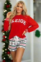 Woman wearing SLEIGH GIRL SLEIGH PJ set with red top and festive snowflake print shorts, perfect for Christmas lounging.