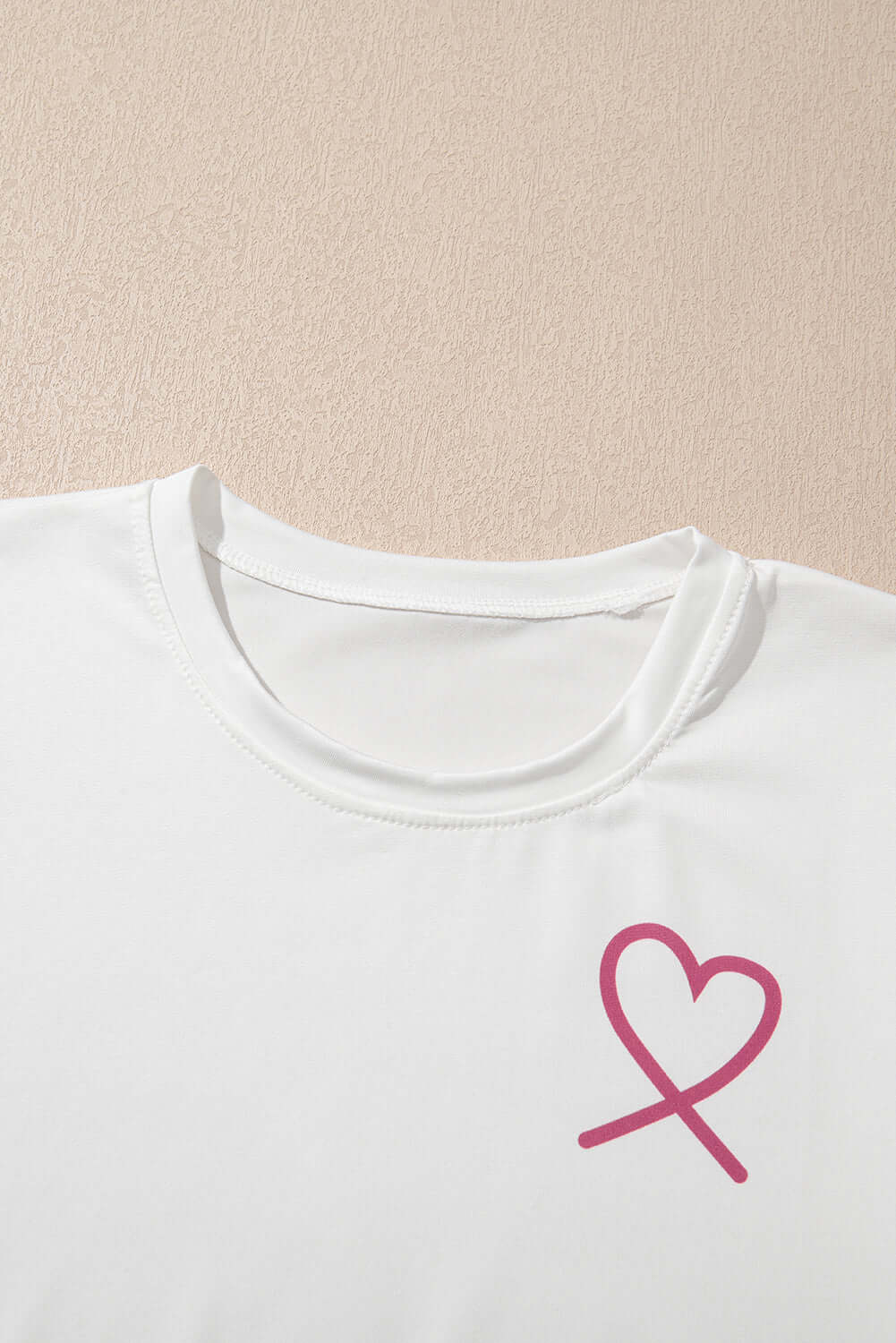 White top featuring a pink heart logo on the chest, perfect for casual and comfy outfits.