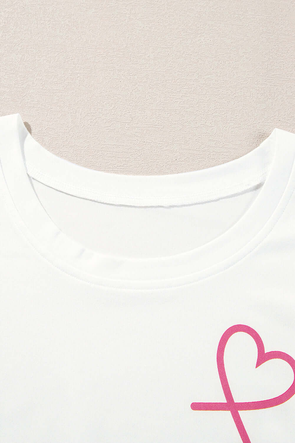 Close-up of a white lounge set tank top with a pink heart design, highlighting comfy style for relaxation.