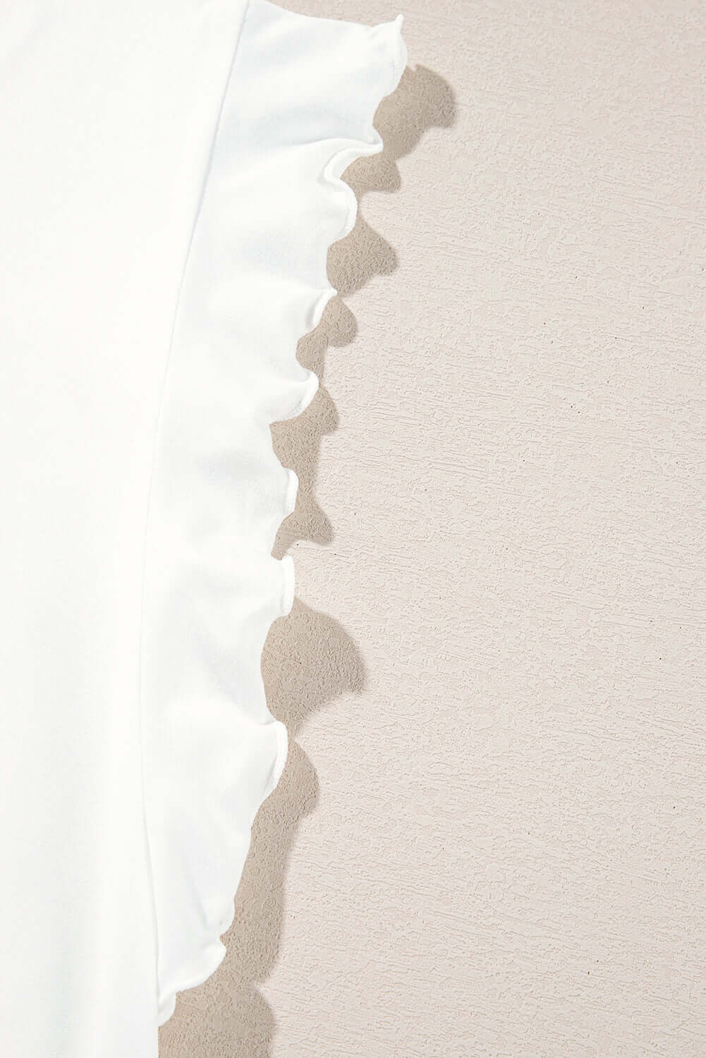 Close-up of ruffled sleeve detail on a white garment, showcasing soft fabric and delicate design.