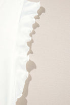 Close-up of ruffled sleeve detail on a white garment, showcasing soft fabric and delicate design.