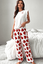 Woman in cozy Love Language Lounge Set featuring heart-print pants and ruffled tank top, perfect for lounging.