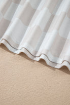 Checkered fabric close-up showing beige and white pattern, perfect for stylish home decor or lounge wear.