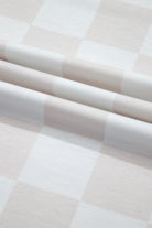 Close-up of neutral-toned checkered fabric, highlighting soft folds and breathable texture for lounge wear.