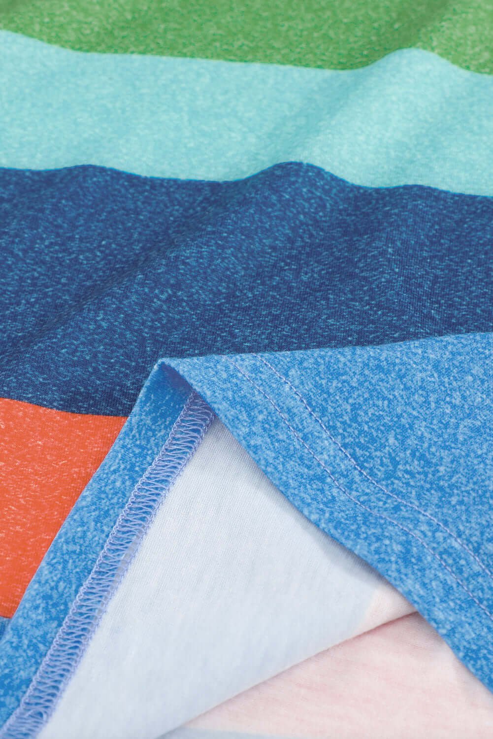 Color block fabric close-up featuring vibrant green, blue, and orange stripes, showcasing soft and breathable textile.