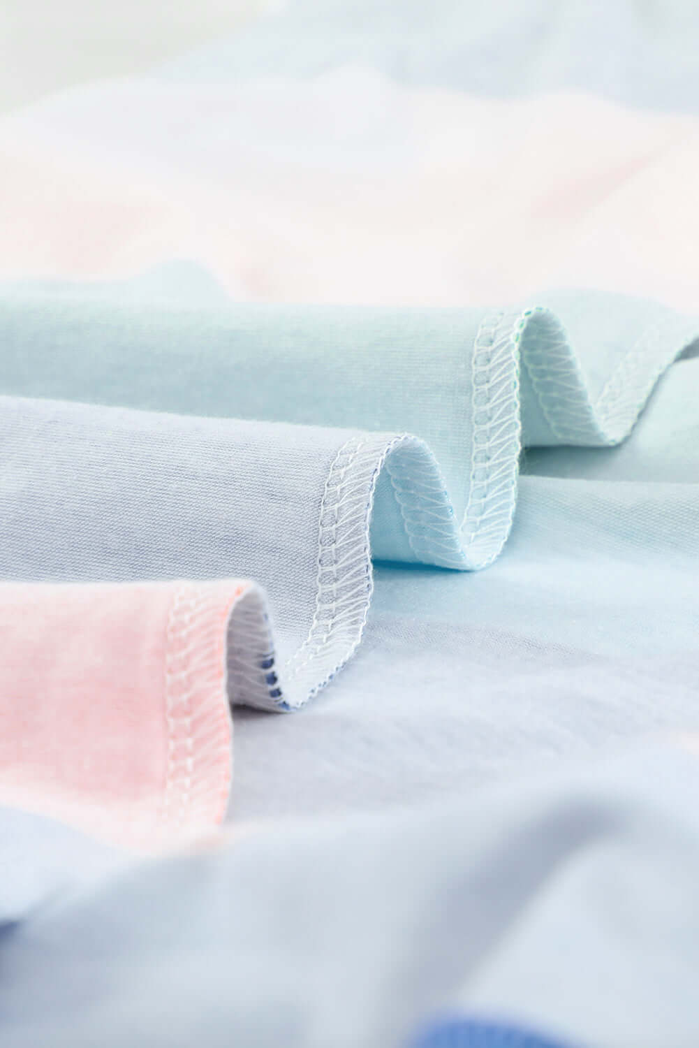 close-up of soft color block fabric showing pastel blue and pink hues, showcasing texture and stitching details.