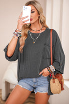 Woman wearing Lines Drawn Top in Charcoal Gray with ribbed knit fabric, paired with denim shorts and accessorized with bracelets.