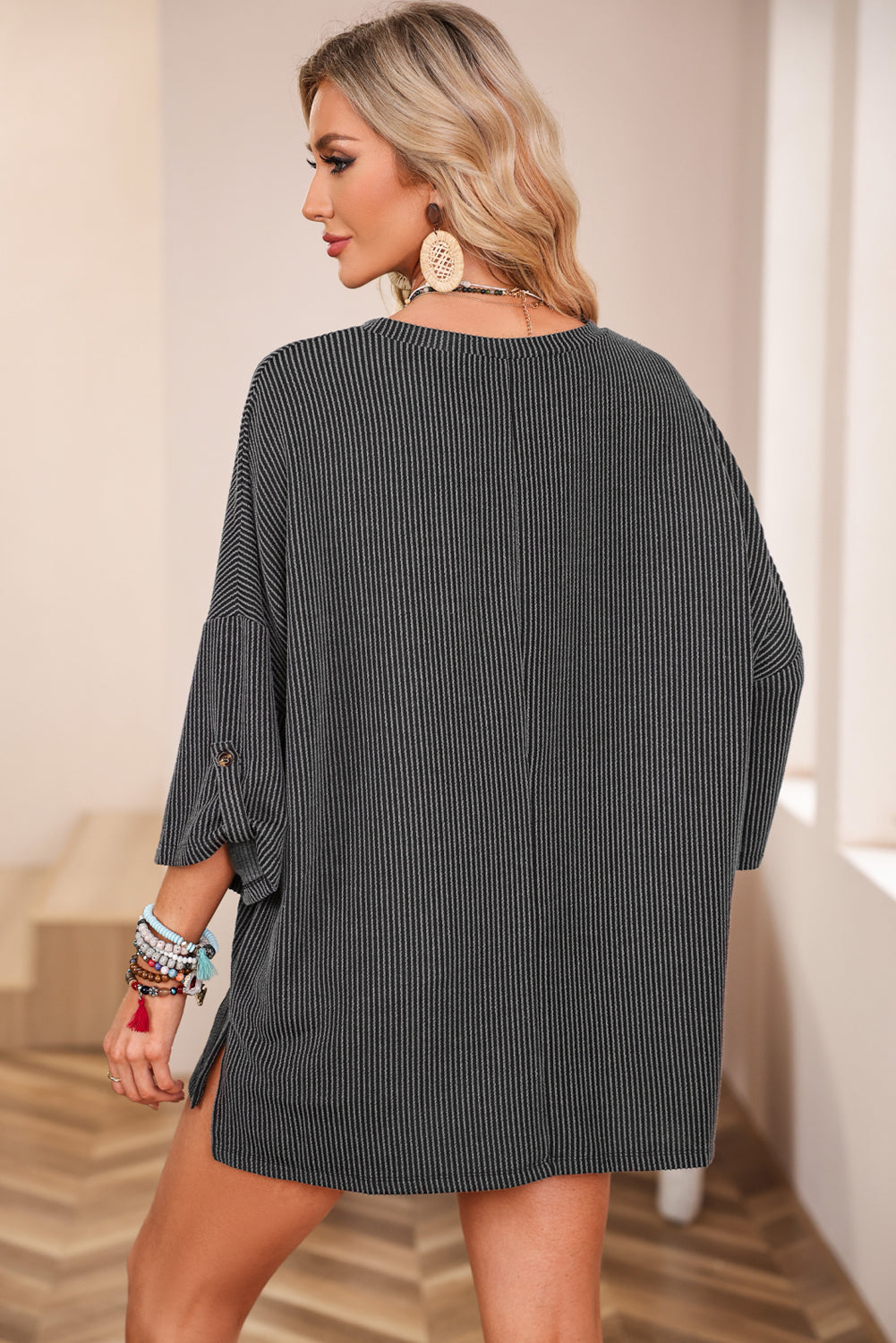 Oversized charcoal gray ribbed knit top with roll-tab sleeves and chest pocket, worn by woman in stylish setting.