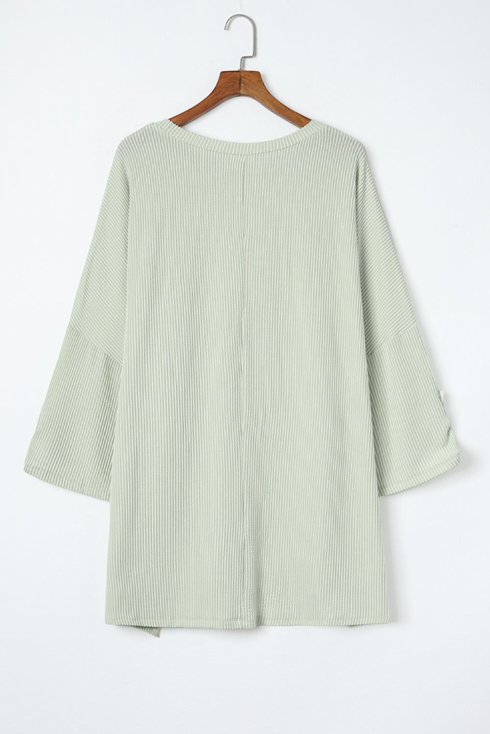 Sage green ribbed knit Lines Drawn Top with roll-tab sleeves on a hanger.