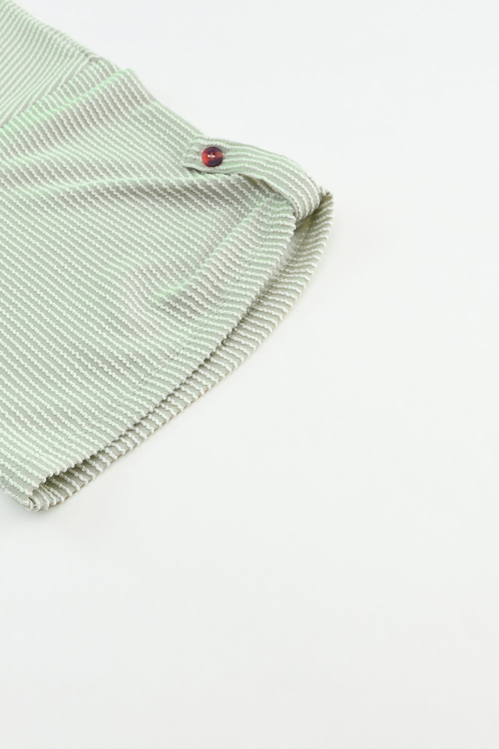 Sage green ribbed knit fabric detail with roll-tab sleeve button on the Lines Drawn Top.