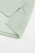 Close-up of sage ribbed knit fabric with roll-tab sleeve detail on Lines Drawn Top.