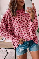 Woman wearing a pink leopard print long sleeve top with relaxed fit, paired with denim shorts, showcasing a casual style.