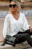 Chic white Lace for Days top with V-neck and balloon sleeves, styled with black pants and a clutch.