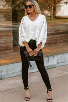 Model wearing the Lace for Days top in white with balloon sleeves, styled with black jeans and handbag.