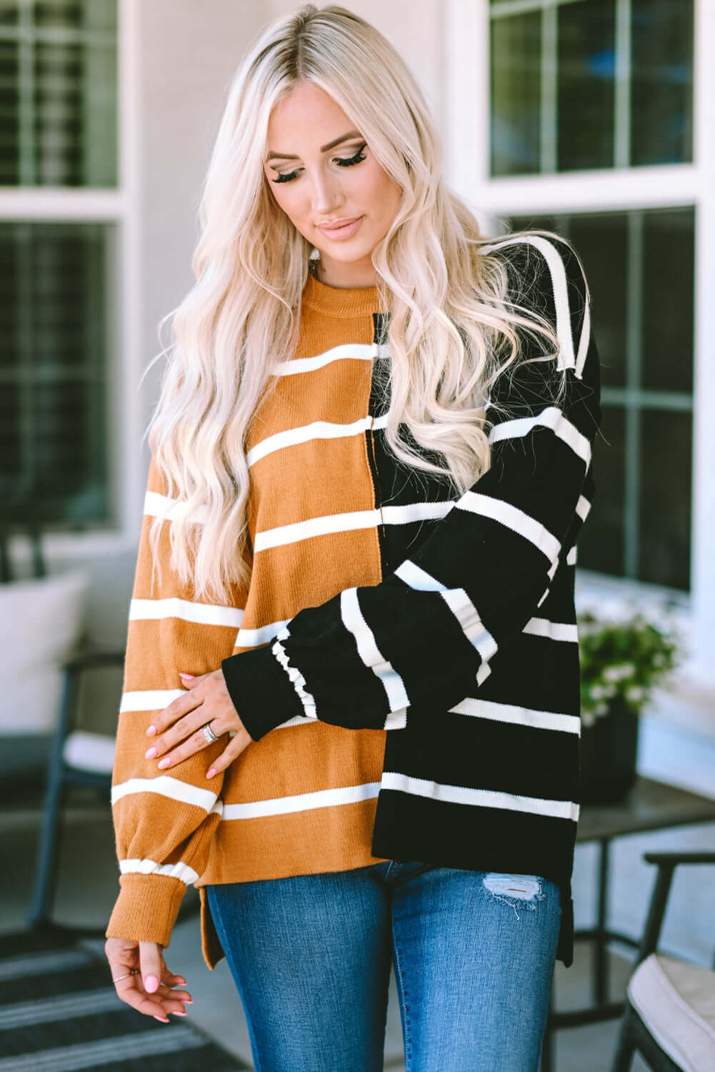 Woman wearing HARVEST SPICE TOP, an oversized striped top with contrast patchwork design, in a trendy outdoor setting.