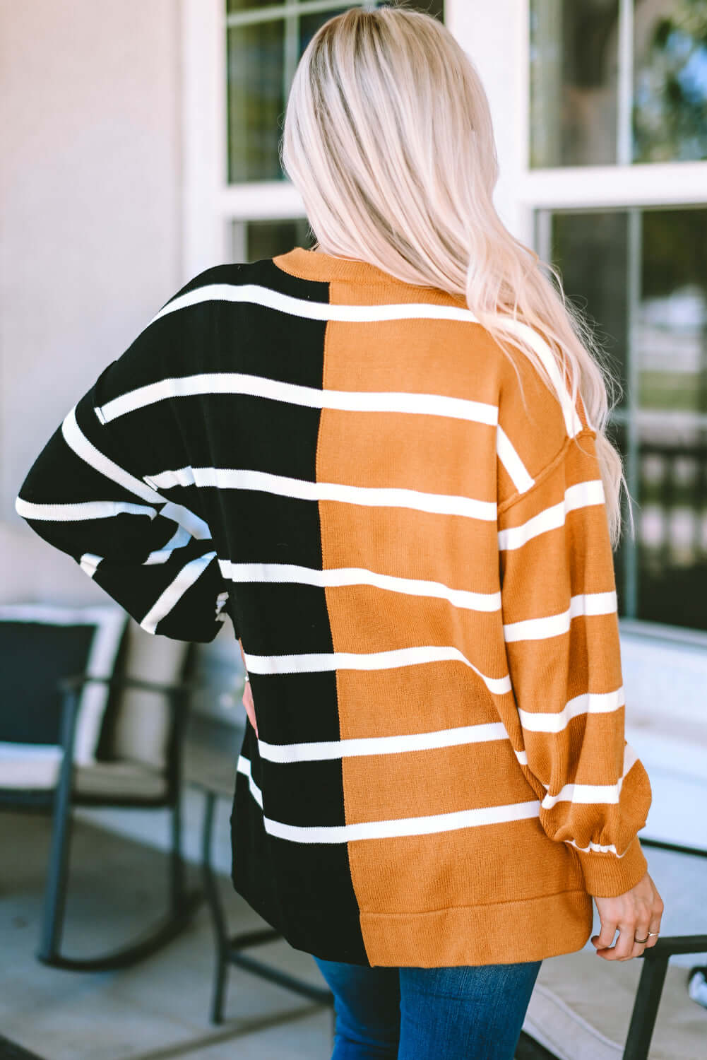 Woman wearing HARVEST SPICE TOP, an oversized striped sweater in black and orange with dropped shoulders and relaxed fit.