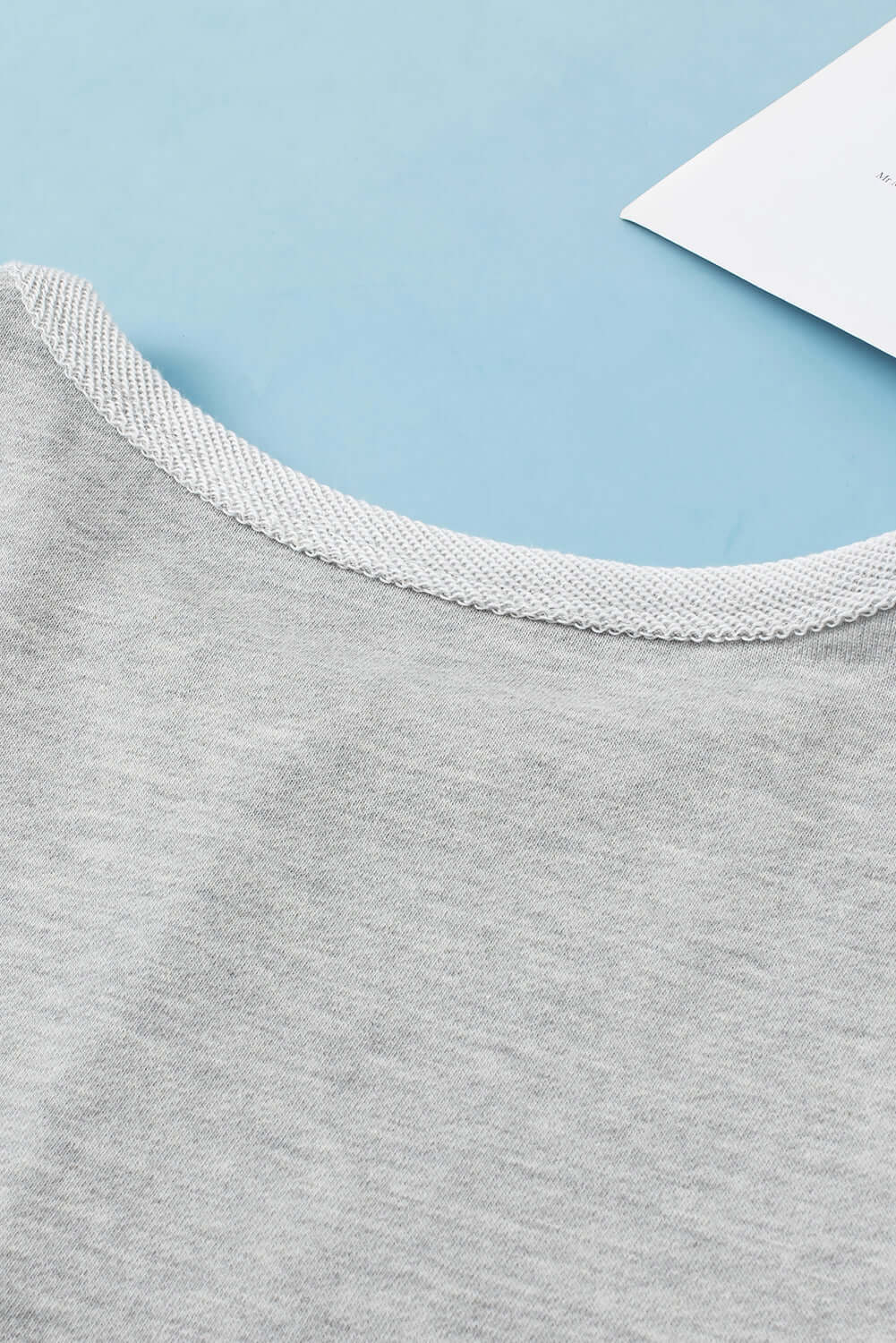 Close-up of the READ BETWEEN THE LINES Top by Vivian-Lu showcasing its soft fabric and round neckline in a subtle patchwork design.