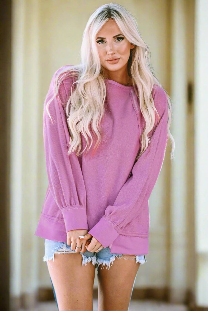 Model wearing a pink BEAUTY IN MOTION top by Vivian-Lu, featuring exposed seam detailing and relaxed fit. Perfect for casual or athletic wear.